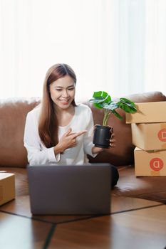 Starting small business entrepreneur of independent young Asian woman online seller using a computer showing products to a customer before making a purchase decision. SME delivery concept.