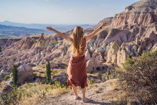 Young woman exploring valley with rock formations and fairy caves near Goreme in Cappadocia Turkey.