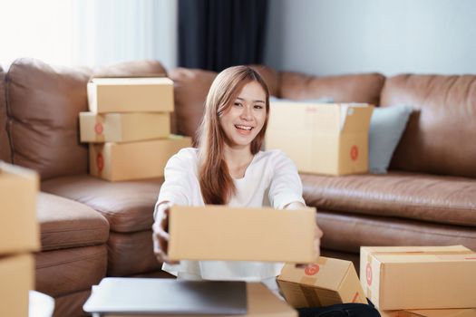 Starting small business entrepreneur of independent Asian female online seller packing products to send to customers and SME delivery concept.