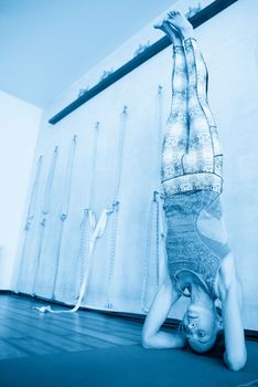 Young yoga woman standing on head in shirshasana. profile view