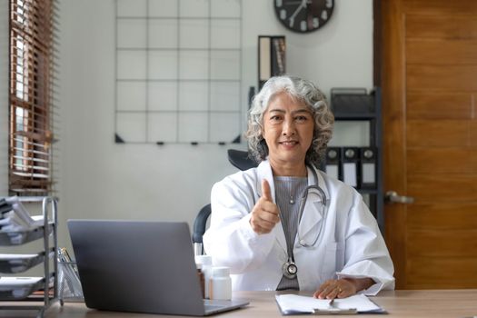 Portrait of Asian doctor working at her table in clinic..