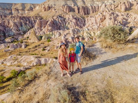 Happy family mother, father and son tourists exploring valley with rock formations and fairy caves near Goreme in Cappadocia Turkey.