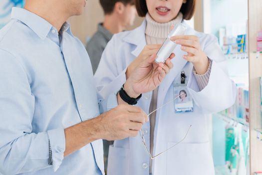 Closeup professional pharmacist advise or explain property of qualified medical product to customer in pharmacy, druggist answer to client healthcare inquiry, medical service and consultation concept.
