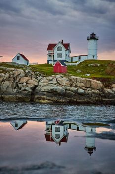 Image of Morning light of Maine lighthouse reflecting in puddle on coast