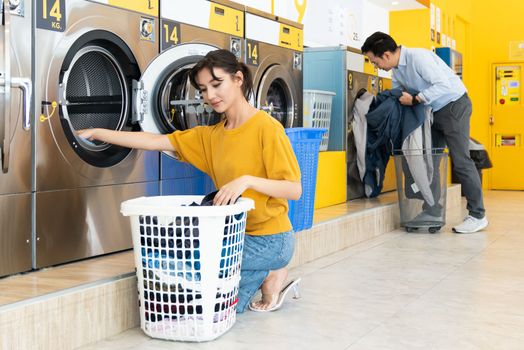 Asian people using qualified coin operated laundry machine in the public room to wash their cloths. Concept of a self service commercial laundry and drying machine in a public room.