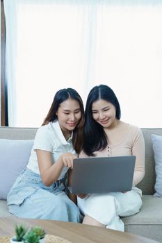 lgbtq, lgbt concept, homosexuality, portrait of two asian women posing happy together and loving each other while playing computer laptop on sofa.