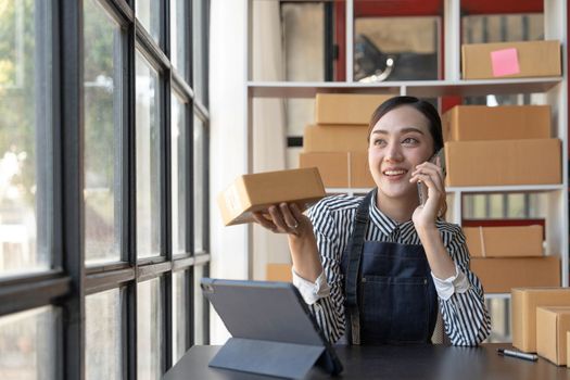 Small start-up business owners using computers and phones at work, salespeople, checking production orders. Pack products to ship to customers, sell ecommerce shipping ideas..