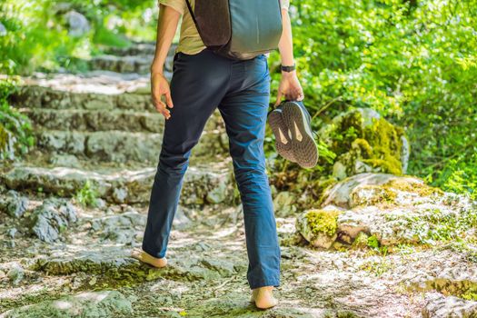 Man tourist climb barefoot the mountain to the Ostrog. It is a tradition to climb barefoot. Monastery of Ostrog, Serbian Orthodox Church situated against a vertical background, high up in the large rock of Ostroska Greda, Montenegro. Dedicated to Saint Basil of Ostrog.