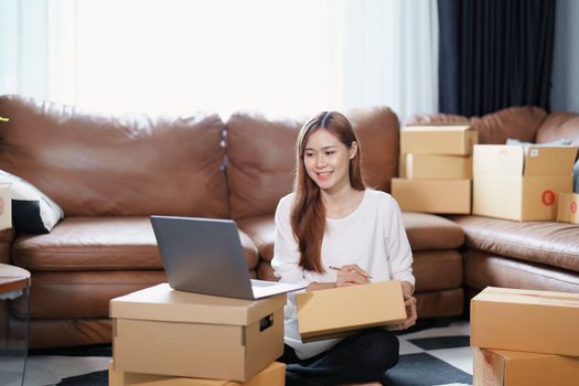 Starting small business entrepreneur of independent Asian female online seller packing products to send to customers and SME delivery concept.