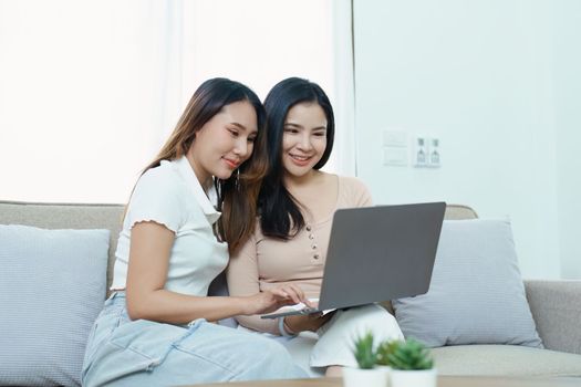 lgbtq, lgbt concept, homosexuality, portrait of two asian women posing happy together and loving each other while playing computer laptop on sofa.