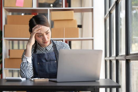 Teenager asian girl freelancer small business serious working at home office with laptop packaging delivery online market on purchase orders to customer