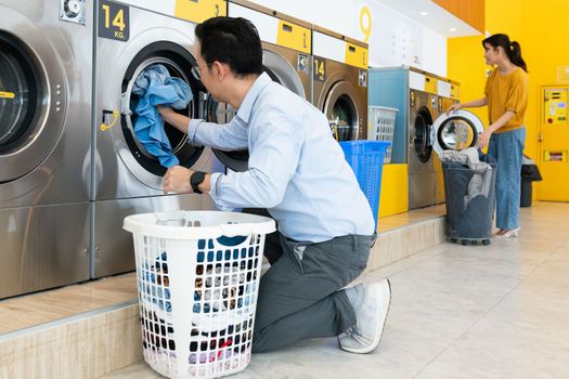 Asian people using qualified coin operated laundry machine in the public room to wash their cloths. Concept of a self service commercial laundry and drying machine in a public room.