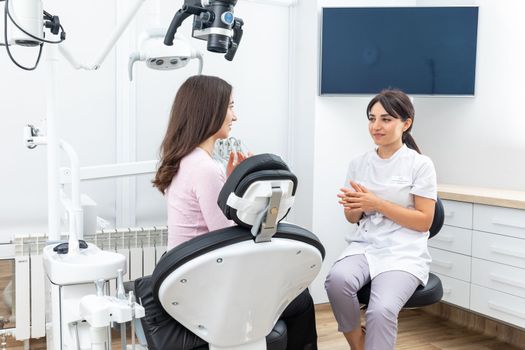 Female dentist explaining patient treatment during appointment in dental clinic