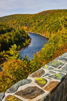 Image of Stone wall with yellow graffiti with out of focus river and fall forest behind