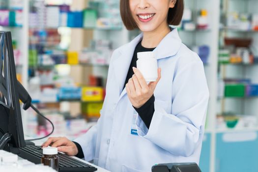 Closeup portrait of a young pharmacist and qualified pharmaceutical, medicine pill container or bottle mockup for copyspace at pharmacy. Drugstore concept with various medicine pills on