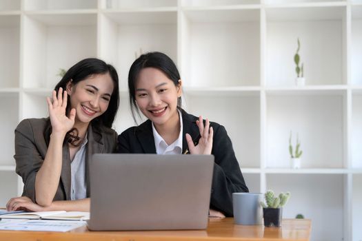 Two young Asian business woman talk, consult, discuss working with new startup project idea presentation analyze plan marketing and investment in the office...