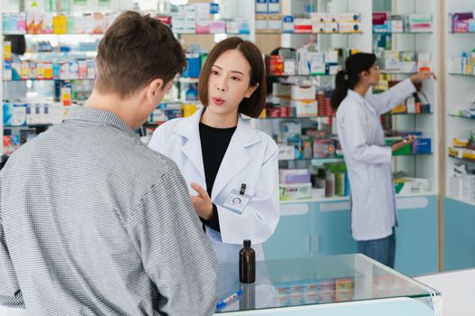 Professional pharmacist advise or explain property of qualified medical product to customer in pharmacy, druggist answer to client healthcare inquiry, medical service and consultation concept.