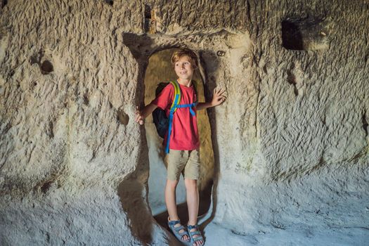 Boy tourist exploring valley with rock formations and fairy caves near Goreme in Cappadocia Turkey.