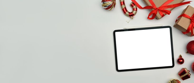Digital tablet, gift boxes and Christmas ornaments on white background. Top view with copy space for your advertise text.