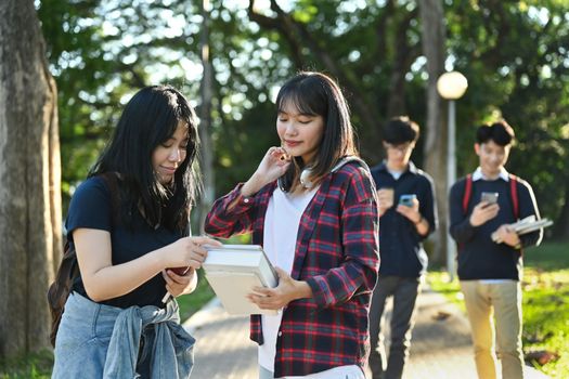 Shot of two friendly female students are talking to each other after classes while walking in university campus outdoors.