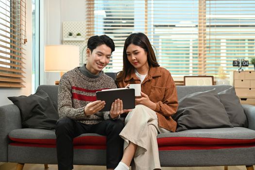 Young asian couple using digital tablet, enjoy spending time together on winter holidays.