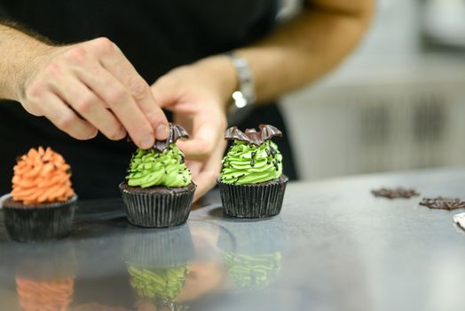 artisan chef preparing handmade with icing and chocolate spider vampire topper