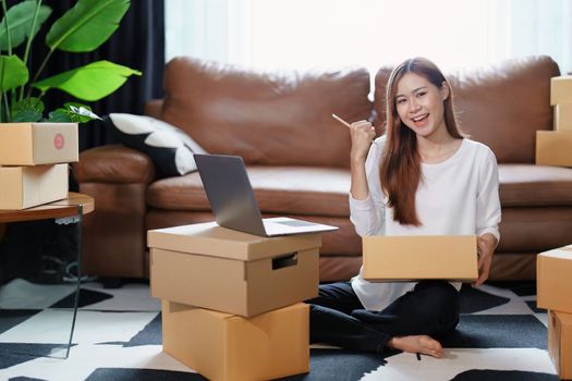 Starting small business entrepreneur of independent Asian female online seller packing products to send to customers and SME delivery concept.