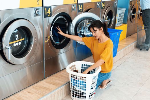 Asian people using qualified coin operated laundry machine in the public room to wash their cloths. Concept of a self service commercial laundry and drying machine in a public room.