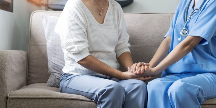 Happy patient is holding caregiver for a hand while spending time together. Elderly woman in nursing home and nurse...