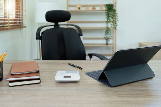 Tablet computer, notebook, calculator and coffee cup on the desk in the office.