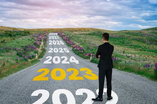The 2023 New Year journey and future vision concept . Businessman traveling on highway road leading forward to happy new year celebration in beginning of 2021 for fresh and successful start .