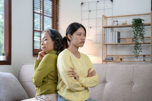 Family sit on couch having dispute, grown up daughter proves her right aggressively argue with elderly mother, 60s mom in despair due to misunderstanding. Generational gap, conflicts at home concept.