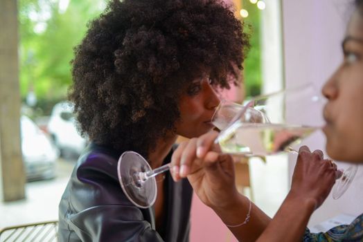 LGBT. Lesbian couple together concept. Couple of young asian woman and african woman drinking and having fun in a bar.