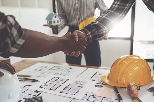 Architect and engineer construction workers shaking hands after finish an agreement in the office construction site, success collaboration concept.