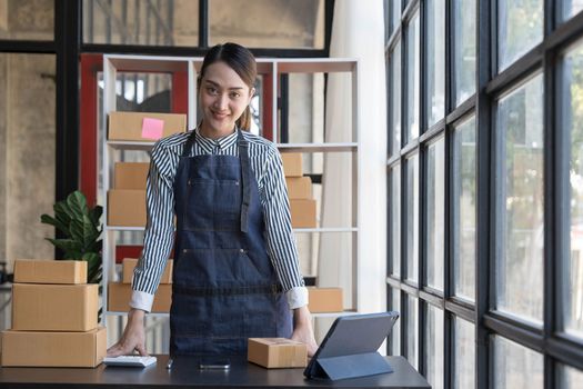 Portrait of Asian young woman SME working with a box at home the workplace.start-up small business owner, small business entrepreneur SME or freelance business online and delivery concept...