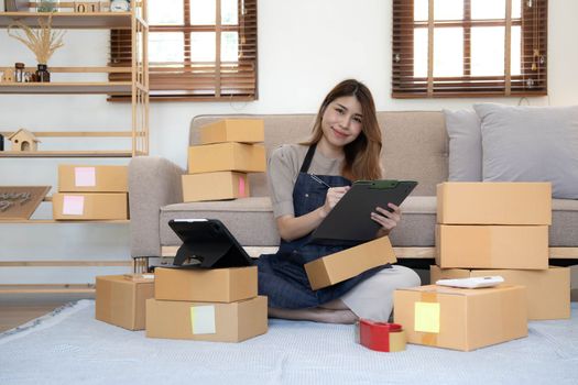 Portrait of Starting small businesses SME owners female entrepreneurs working on receipt box and check online orders to prepare to pack the boxes, sell to customers