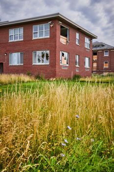 Image of Grassy fields outside of abandoned brick buildings