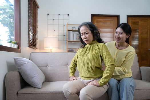 Asian daughter giving an elderly mother a relaxing massage while sitting on the sofa.