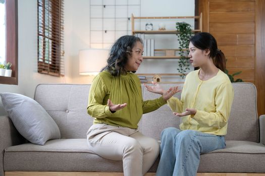 Family sit on couch having dispute, grown up daughter proves her right aggressively argue with elderly mother, 60s mom in despair due to misunderstanding. Generational gap, conflicts at home concept.