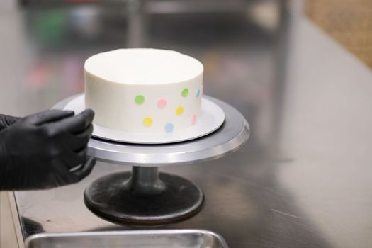 decorating a frosted cup cakes with multi colored dots