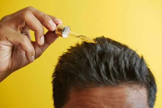  young men applying essential oils on his hair .