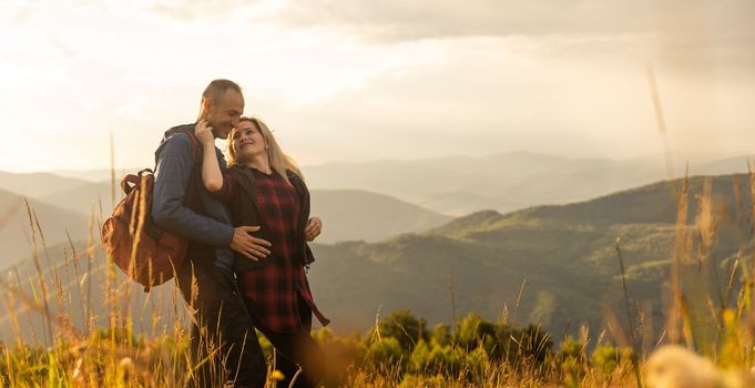 travel, tourism and people concept - happy couple with backpacks having fun over mountains background.