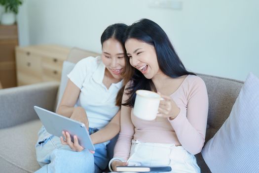 lgbtq, lgbt concept, homosexuality, portrait of two asian women posing happy together and loving each other while playing tablet at sofa.