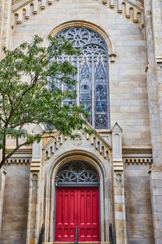 Image of Front of Christian Church with vibrant red doors and stained glass 