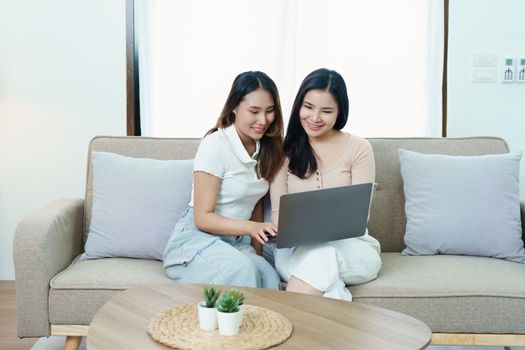 lgbtq, lgbt concept, homosexuality, portrait of two asian women posing happy together and loving each other while playing computer laptop on sofa.