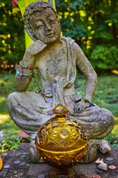 Image of Detail of stone Tibetan Mongolian Buddhist statue surrounded by natural donations