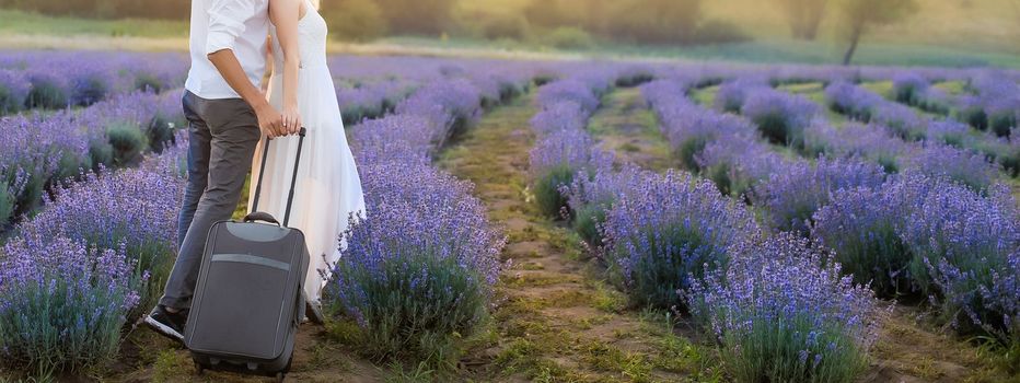 Smiling young couple embracing at the lavender field, holding hands, walking