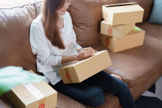 Starting small business entrepreneur of independent Asian female online seller packing products to send to customers and SME delivery concept.