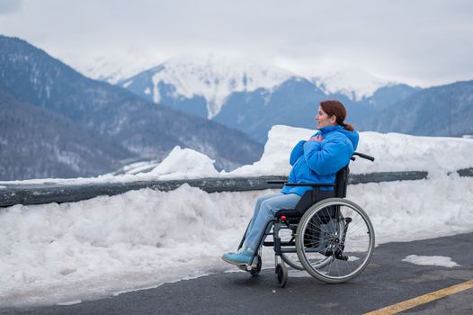 Caucasian woman in a wheelchair travels in the mountains in winter