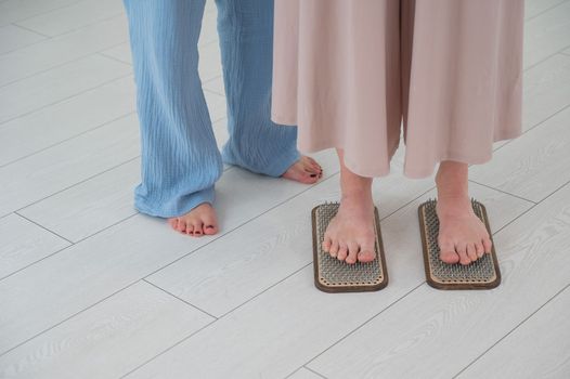 Caucasian woman stands on sadhu boards with therapist support